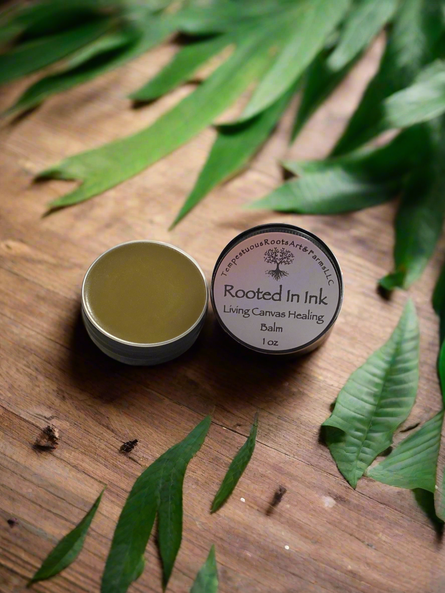 1 oz Tattoo balm Rooted in Ink in a metal tin on a wood board with a blurred background with leaves