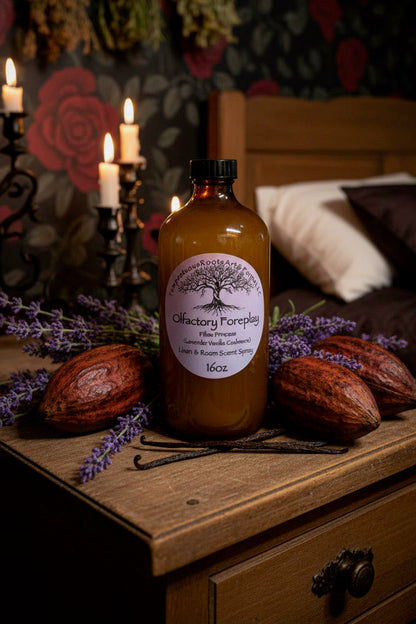 An amber glass bottle of Olfactory Foreplay, "pillow princess" scent, handcrafted by Tempestuous Roots Art & Farms LLC styled on a rustic wooden nightstand with cocoa beans, vanilla beans, lavender, and lit candles in the background.