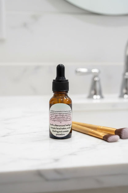 Rooted Mask botanical tattoo and cosmetic aftercare oil with cosmetic brushes on a bathroom counter